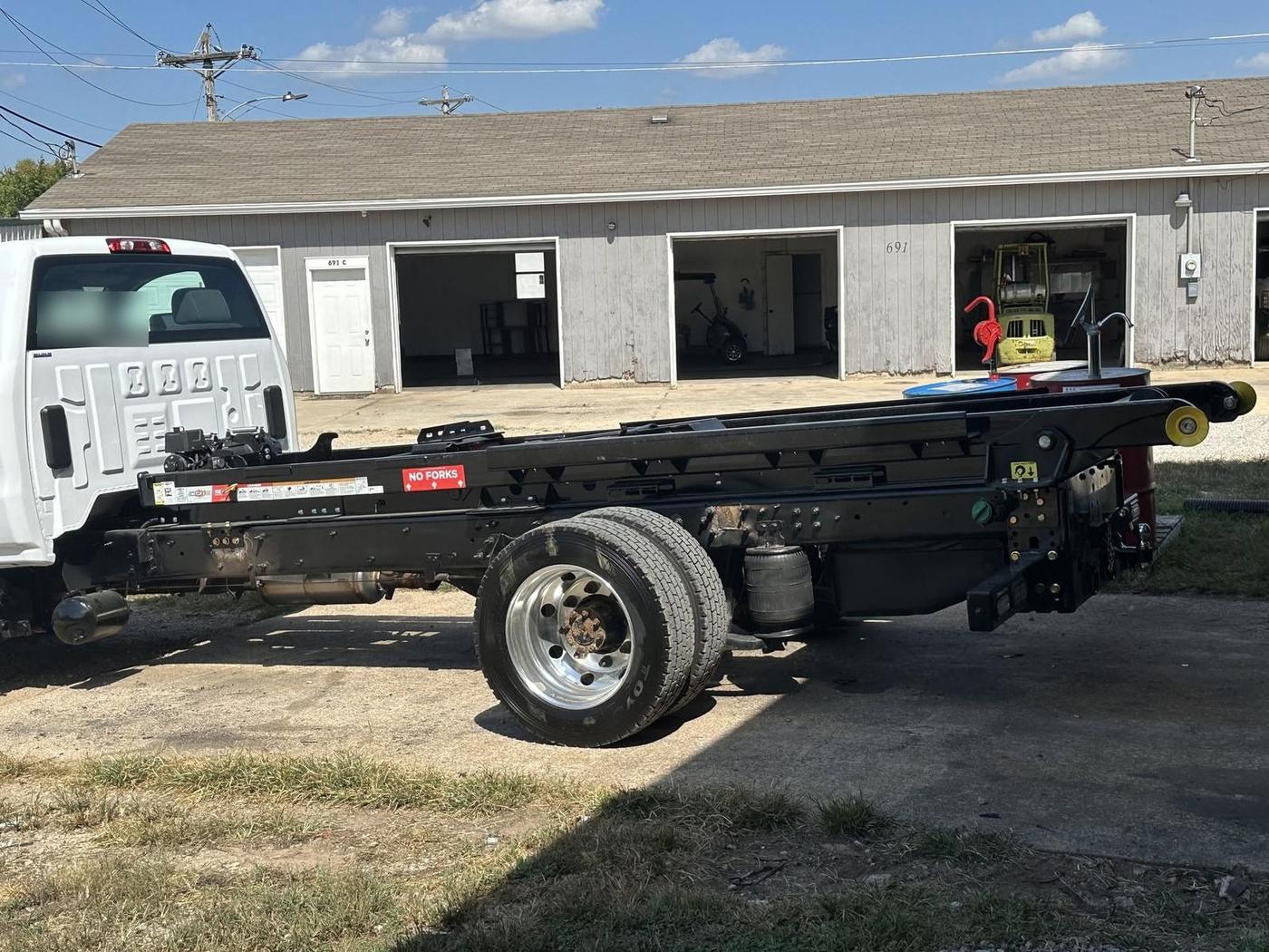 Hook-lift bed system installed on a white cab-and-chassis truck outside the shop