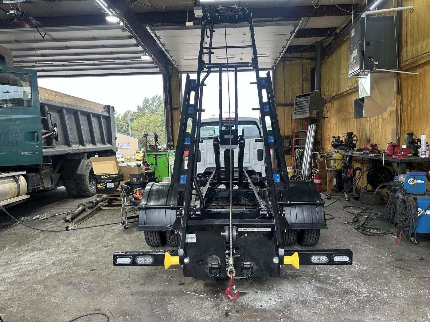 Hook-lift mast raised inside the shop mid-install