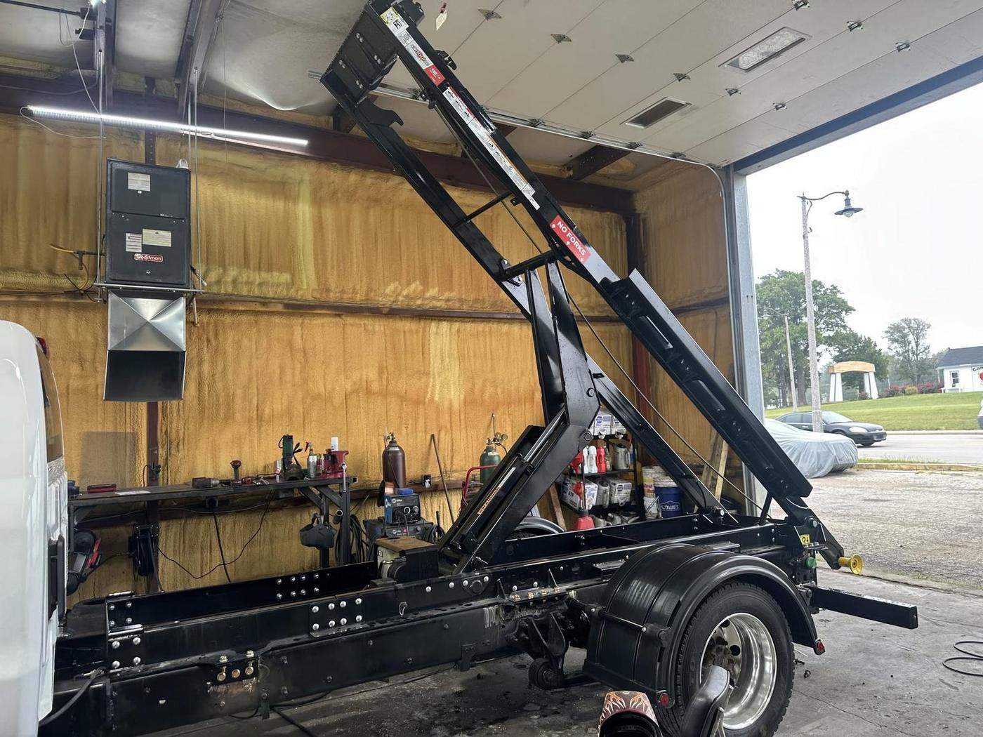 Another angle of a hook-lift upfit with the mast up at the bay door